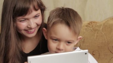 Neşeli küçük çocuk ve annesi dijital tablet kullanma kanepede oturan