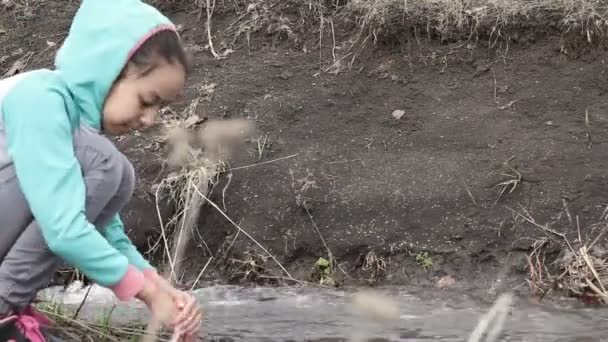 Linda chica sentada en la orilla del arroyo — Vídeos de Stock