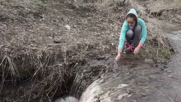 Linda chica sentada en la orilla del arroyo — Vídeos de Stock
