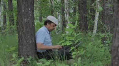 Uzaktan laptop ile doğa üzerinde çalışan adam