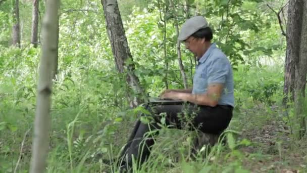 Man arbetar via fjärranslutning med laptop på natur — Stockvideo