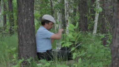 Uzaktan laptop ile doğa üzerinde çalışan adam