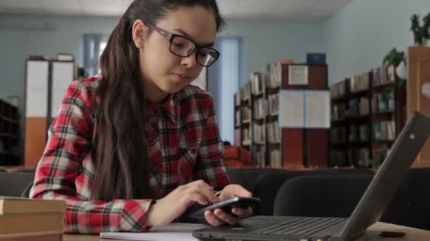 Chica con el pelo largo con gafas que trabajan en la biblioteca de la escuela . — Vídeos de Stock