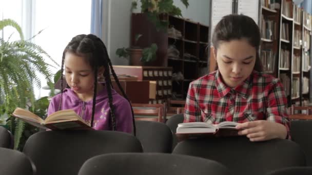 Dwie siostry z długimi włosami w szkolnej bibliotece — Wideo stockowe