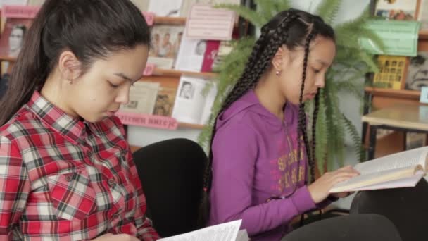 Due sorelle con i capelli lunghi nella biblioteca scolastica — Video Stock