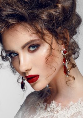 Güzel genç kadın uzun kahverengi saçlı, kırmızı dudaklar, mücevher gelinlikle oldukça pozlar stüdyoda modeli.