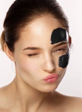 Yüzünde arındırıcı siyah maske olan kadın beyaz arka planda izole edilmiş.