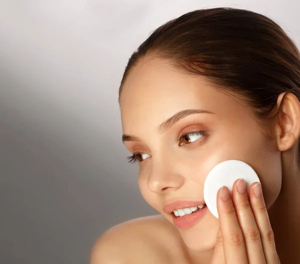 Kvinna applicera torrt pulver med hjälp av kosmetisk kudde på hennes ansiktshud. Foto av attraktiv flicka med perfekt makeup på beige bakgrund. Skönhetsbegreppet Stockbild