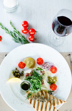 Tartar Roka Salatası ile sığır eti, yumurta sarısı ve kıtır ekmek cips beyaz plaka üzerinde