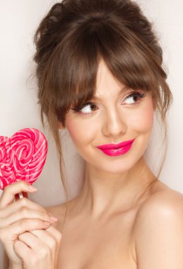 Moda makyaj. Güzellik kız portre renkli lolipop tutan. Sıcak kırmızı dudaklar.