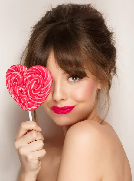 Mode makeup. Skönhet flicka stående håller färgglada lollipop. Varma röda läppar. — Stockfoto