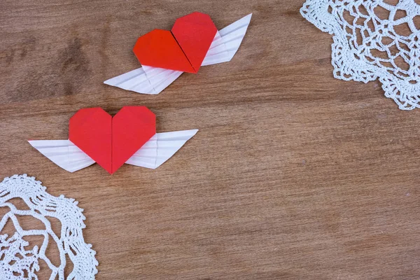 Origami harten met vleugels op een houten achtergrond met kant. Twee harten. — Stockfoto
