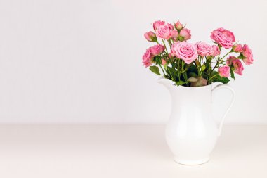 Beyaz sürahi içinde pembe çiçekler.