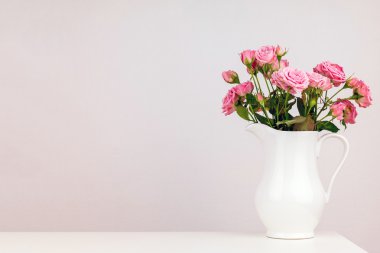 Beyaz sürahi içinde pembe çiçekler.