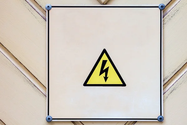 Gevaar voor elektrische sighn op houten lichte gele achtergrond. — Stockfoto