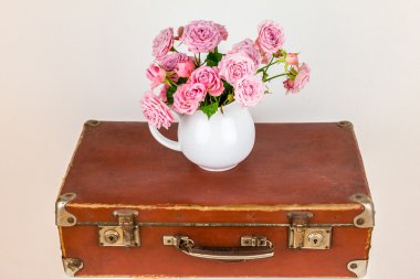 Sürahi eski kahverengi vintage çanta üzerinde çiçeklenir.