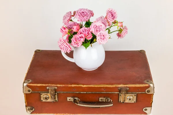 Blumen im Krug auf altem braunen Vintage-Koffer. — Stockfoto