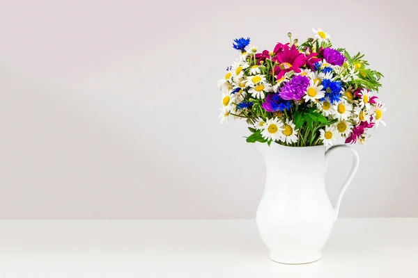 Wilde bloemen in witte keramische kruik. — Stockfoto