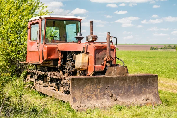 Vecchio trattore arrugginito rosso in un campo — Foto Stock