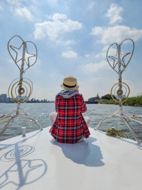 Kız, Kahire 'de Nil' de yelken açan bir geminin pruvasında oturuyor..