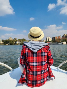 Kız, Kahire 'de Nil' de yelken açan bir geminin pruvasında oturuyor..