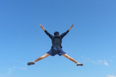 Genç adam mavi gökyüzü manzara karşı atlama.