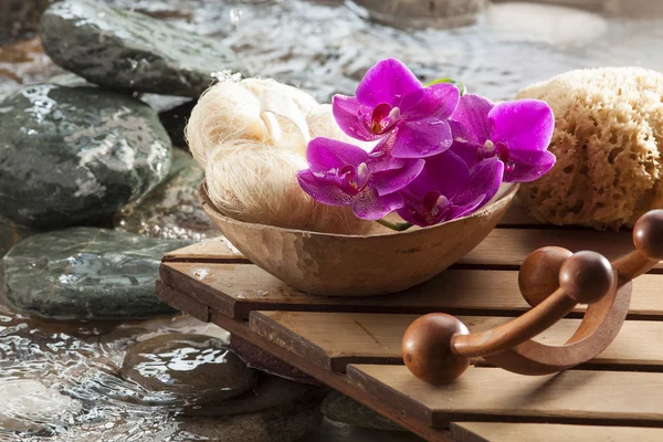 Accesorios junto al agua con esponja y orquídeas rosadas para la belleza y la relajación — Foto de Stock