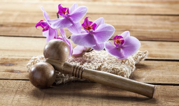 Närbild på luffa handske och orkidéer på trä bakgrund för massage — Stockfoto