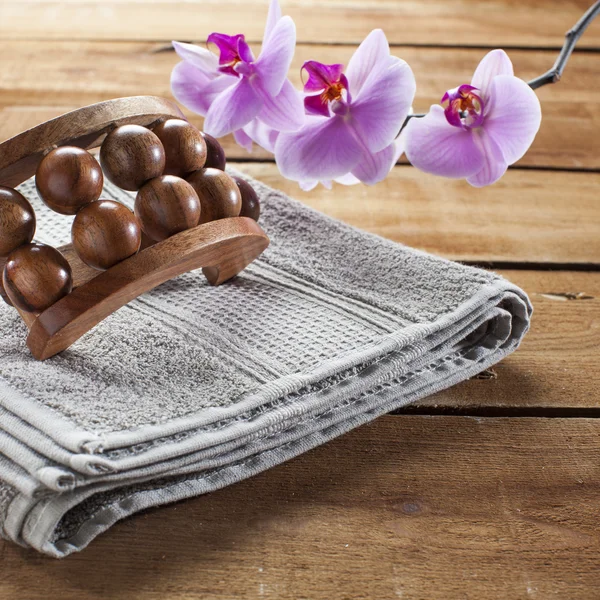 Accessorio per massaggi e fiori di orchidea rosa su fondo legno per il relax — Foto Stock