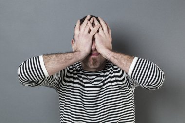 körlük için üzgün yüz gizleme çizgili kazak ile rahatsız adam pişmanlık ifade