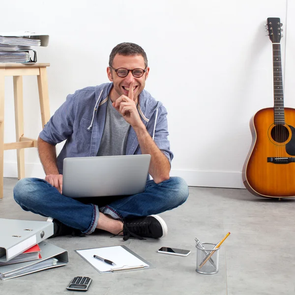Улыбающийся начинающий бизнесмен рабочий бюджет и музыкальный бизнес, сидящий в домашнем офисе — стоковое фото