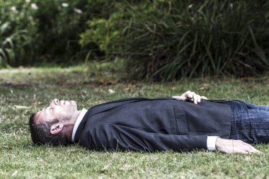 Sleeping businessman lying on grass, textured effect