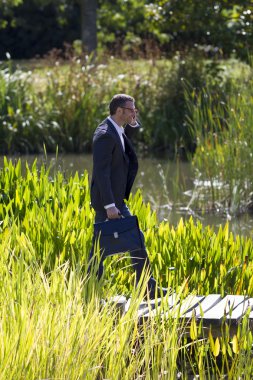 40'lı rahat yürüyüş ve cep telefonu açık havada ile konuşan işadamı