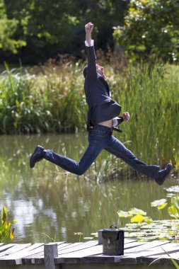 heyecanlı işadamı parkta su yakınında başarı için yüksek atlama