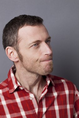 kendinden geçmiş 40'lı yaşlardaki adam kontrol edilmiş gömlekli bir şeye bakıyor.