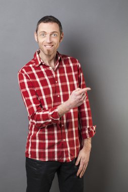 excited 40s man with checked shirt pointing finger to show something on side