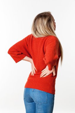 young blond woman suffering from back pain, touching her lower vertebrae