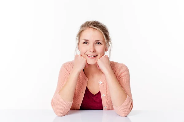 Gorgeous young blond woman sitting in a sparse office laughing with face leaning on both hands — 图库照片