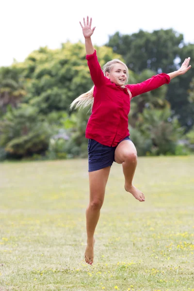 В захваті красива молода жінка стрибає з щастям в сонячному парку — стокове фото