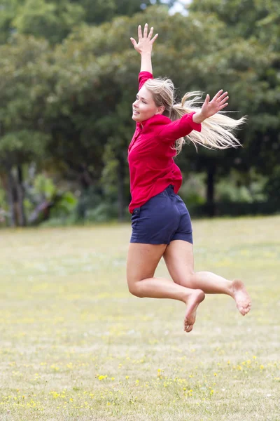 Νεαρή γυναίκα ενθουσιασμένος άλμα υψηλή με ευτυχία στο ηλιόλουστο πάρκο — Φωτογραφία Αρχείου