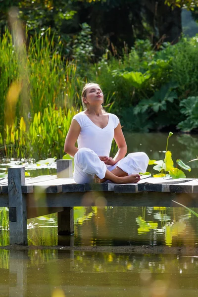 Zen 20s loira ioga menina respirando perto de ambiente aquático — Fotografia de Stock