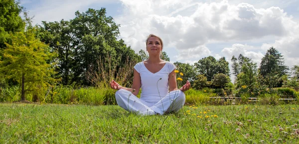 Ejercicio zen al aire libre - sonriente mujer rubia de 20 años meditando en un entorno verde —  Fotos de Stock