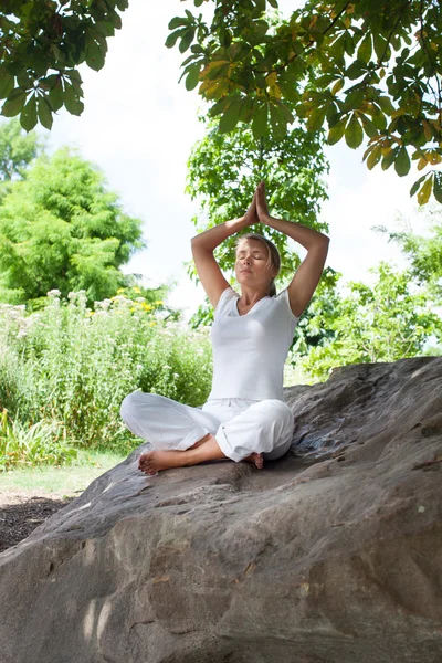 All'aperto zen esercizio - meditando ragazza bionda rilassante sotto un albero su una pietra — Foto Stock