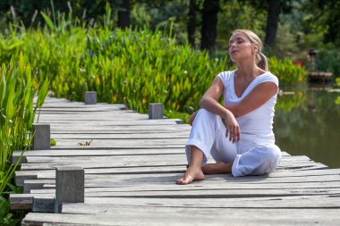 dışında gevşeme - 20s sarışın kadın su kenarında rahatlatıcı güneşte istirahat