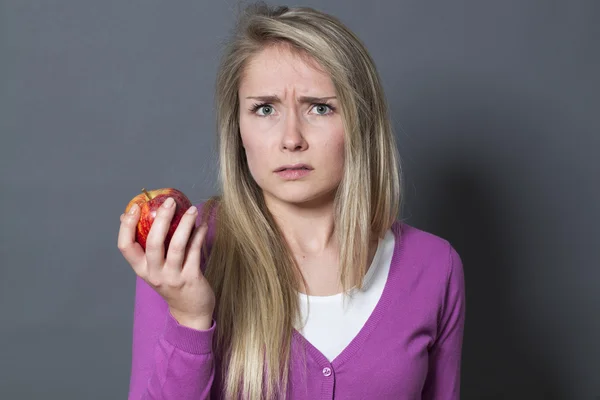 Bister 20s blond flicka inte gillar smaken av ett rött äpple — Stockfoto