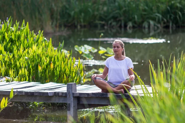 Zen 20s ragazza bionda meditando, ambiente stagno — Foto Stock