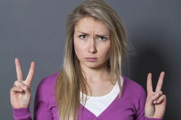 Sulking 20s woman showing two victory signs — 图库照片