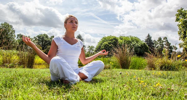 Zen 20s blond girl meditating in green surrondings — Zdjęcie stockowe