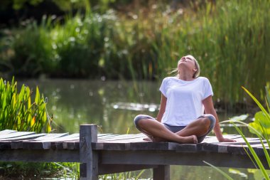 Zen 20'li yaşlarda sarışın kız rahatlatıcı, gölet çevre