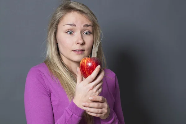Oskyldiga blond flicka hänförd av ett äpple i hennes händer — Stockfoto